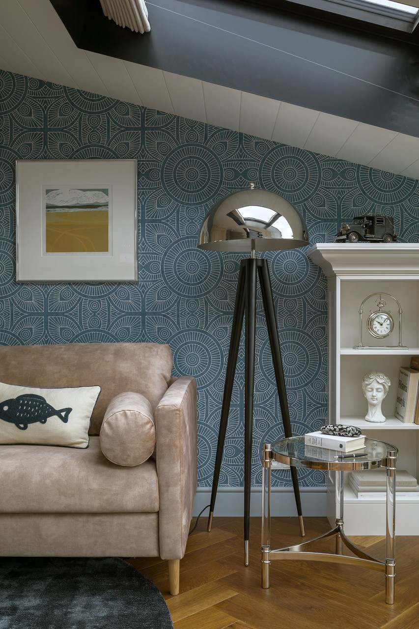 Przytulny salon z designerską lampą i geometryczną tapetą.