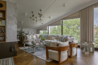Nowoczesny salon z dużą sofą i panoramicznym widokiem na zieleń.