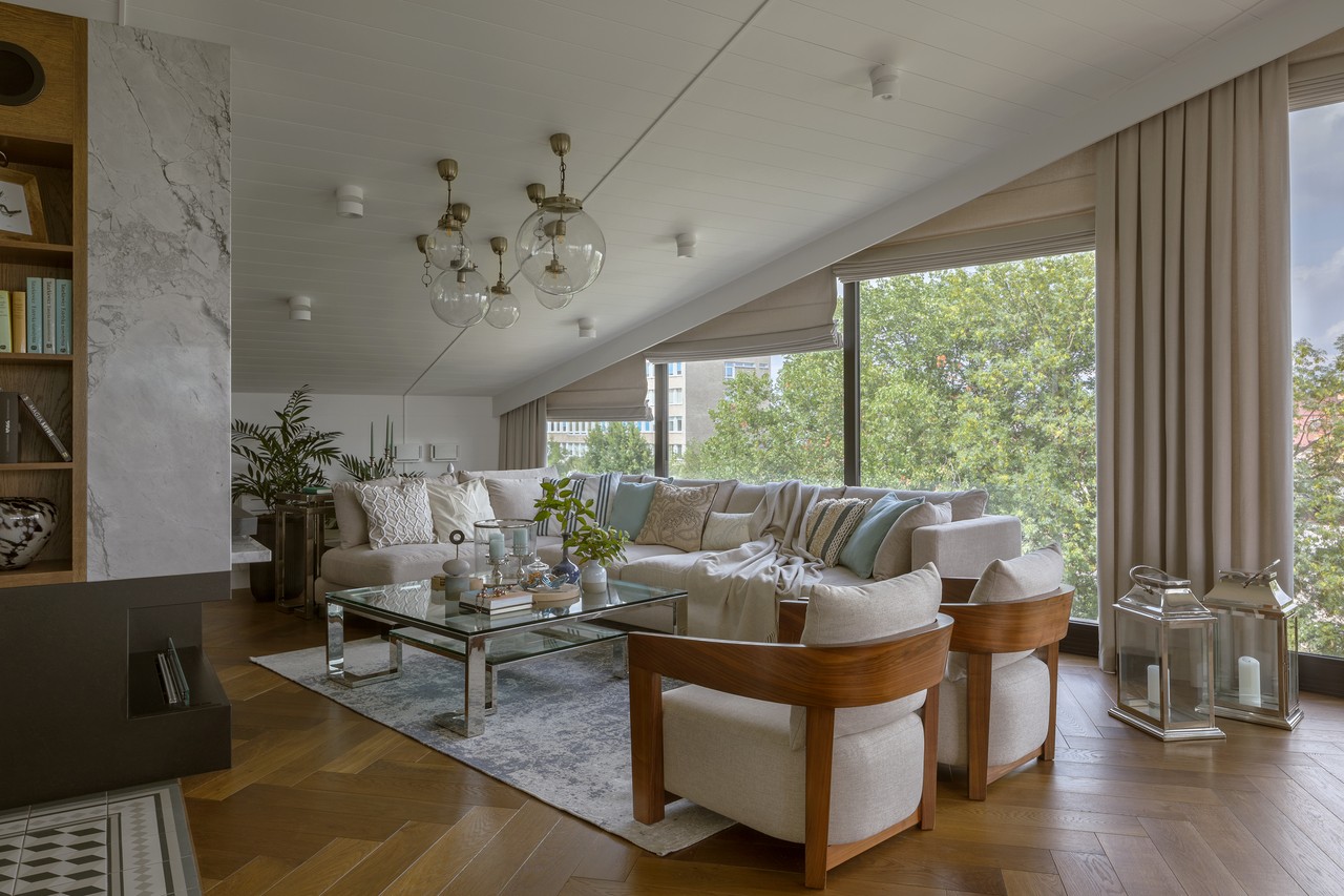 Nowoczesny salon z dużą sofą i panoramicznym widokiem na zieleń.