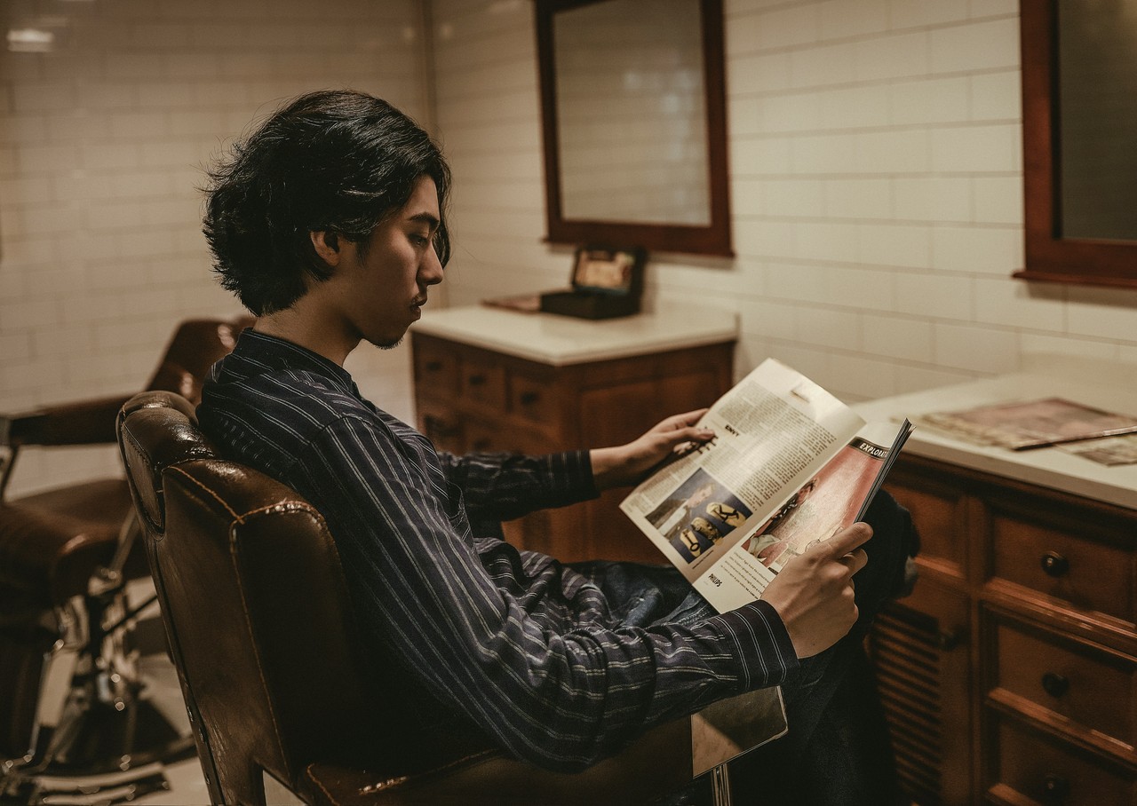 Mężczyzna w stylowym wnętrzu czyta magazyn w fotelu vintage.