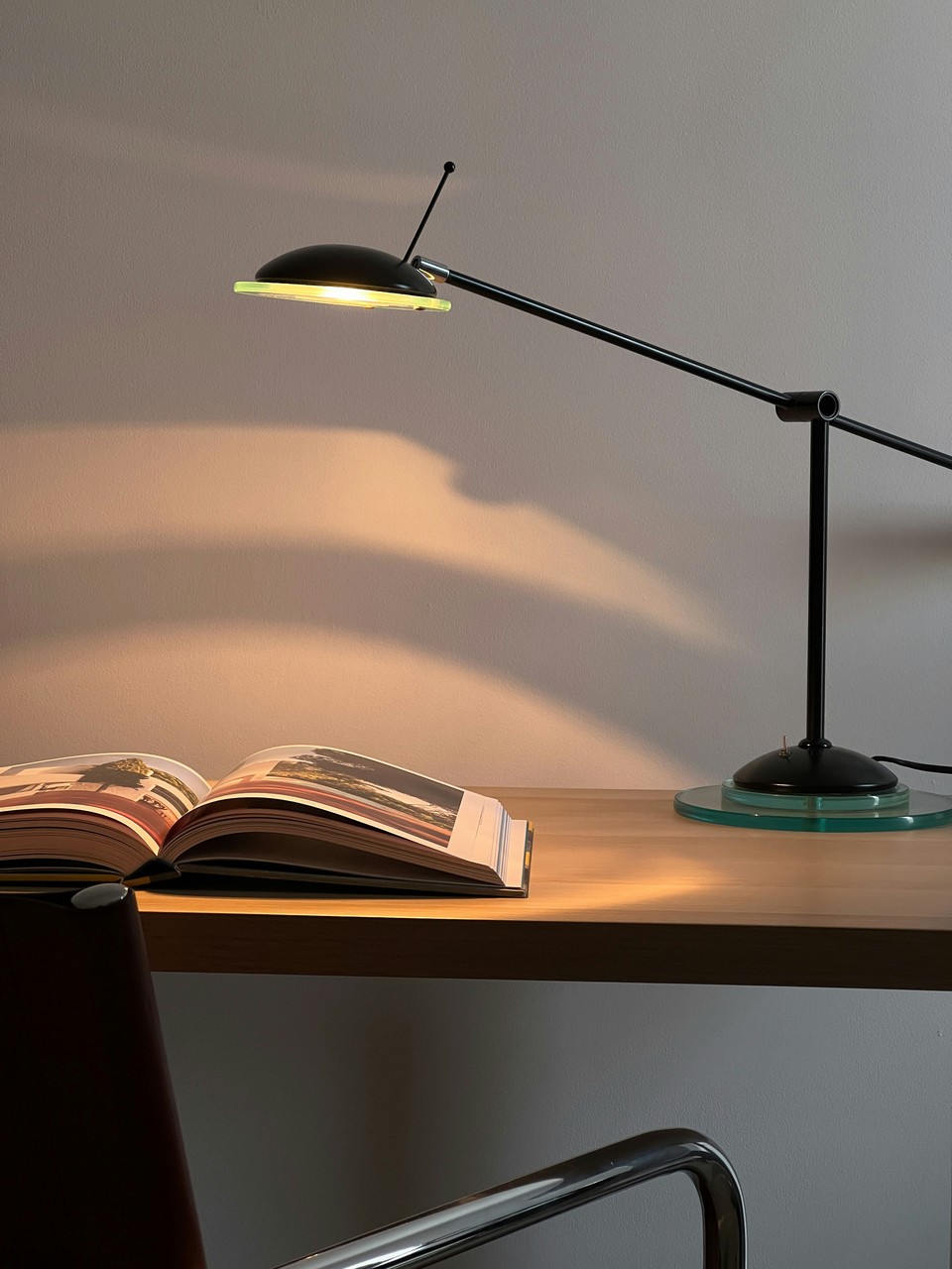 Lampa biurkowa oświetla otwartą książkę na drewnianym blacie.
