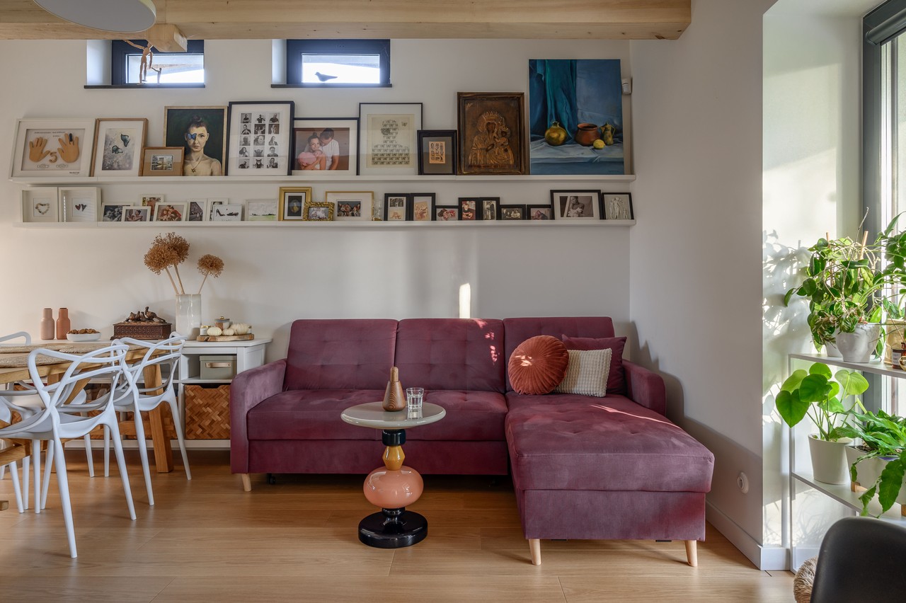 Przytulny salon z fioletową sofą i galerią sztuki na ścianie.