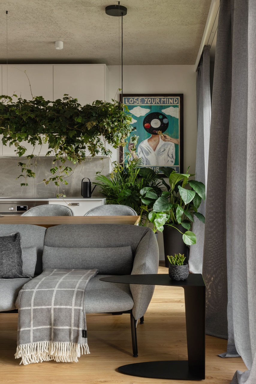 Szara sofa, rośliny doniczkowe i nowoczesny wystrój wnętrza.
