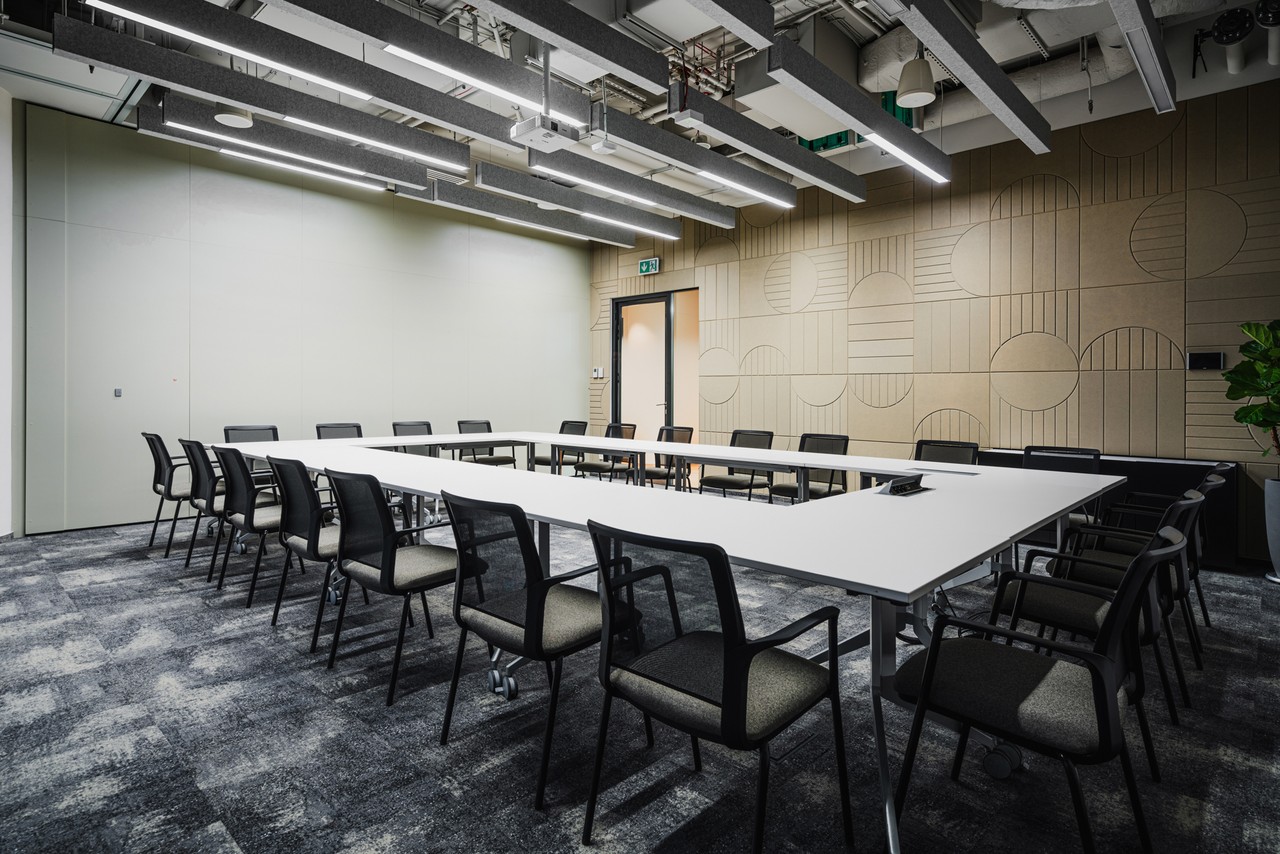 Nowoczesna sala konferencyjna z eleganckim wystrojem i akustycznymi panelami.
