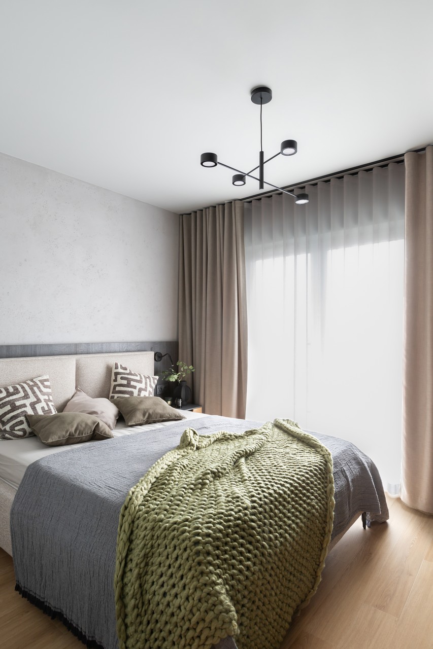 Elegancka sypialnia z designerskim oświetleniem i miękką narzutą.