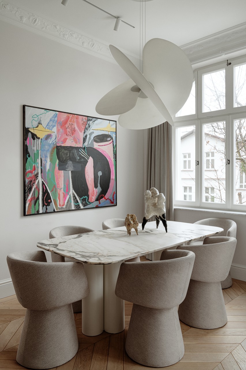 Stylowa jadalnia z marmurowym stołem i designerską lampą.