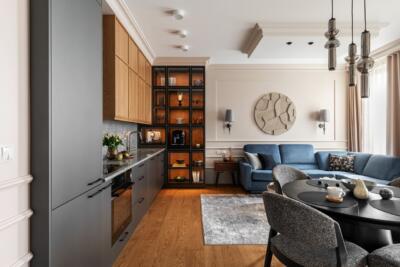 Elegancki salon z kuchnią, drewniane akcenty i niebieska sofa.