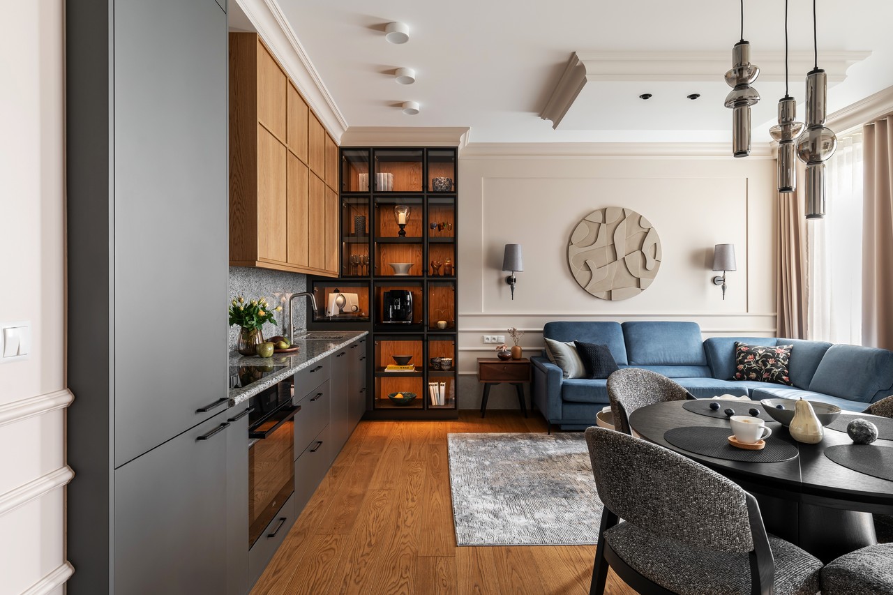 Elegancki salon z kuchnią, drewniane akcenty i niebieska sofa.