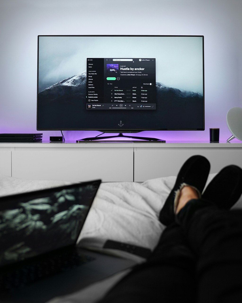 Minimalistyczny salon z dużym telewizorem i laptopem.