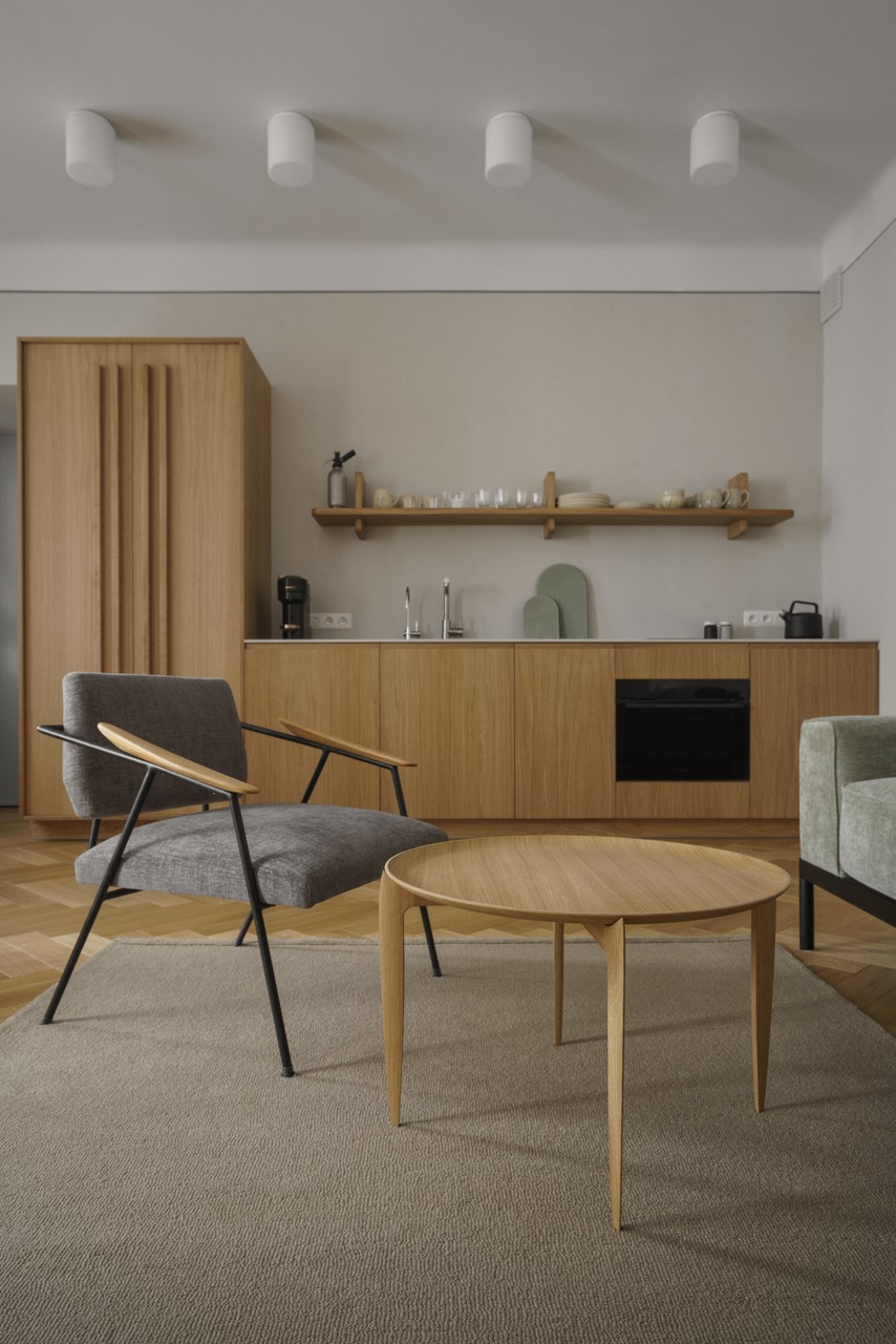 Minimalistyczny salon z drewnianymi meblami i designerskim fotelem.
