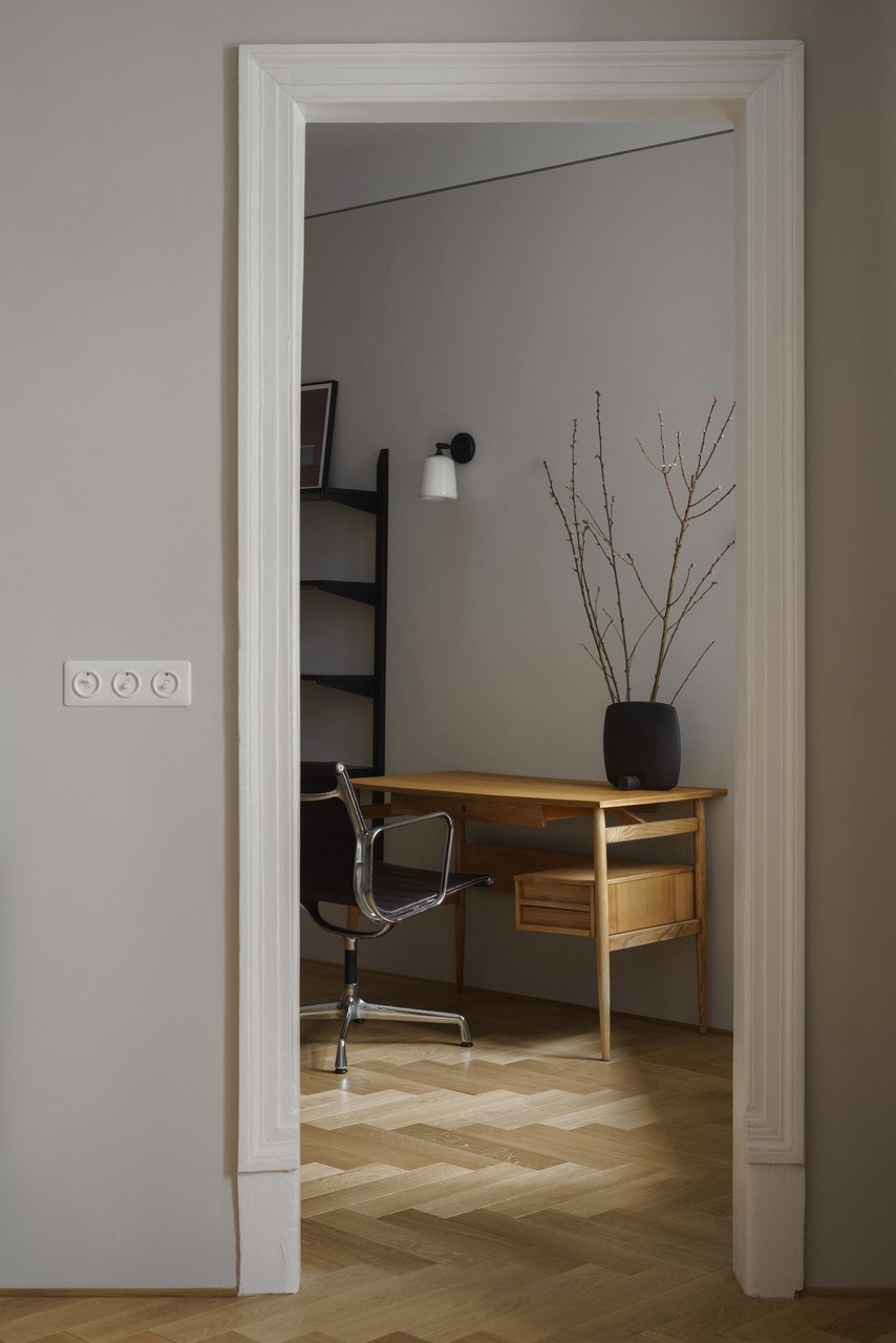 Minimalistyczne biuro z drewnianym biurkiem i eleganckim krzesłem.