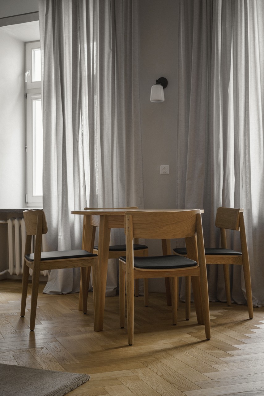 Minimalistyczna jadalnia z drewnianym stołem i krzesłami.