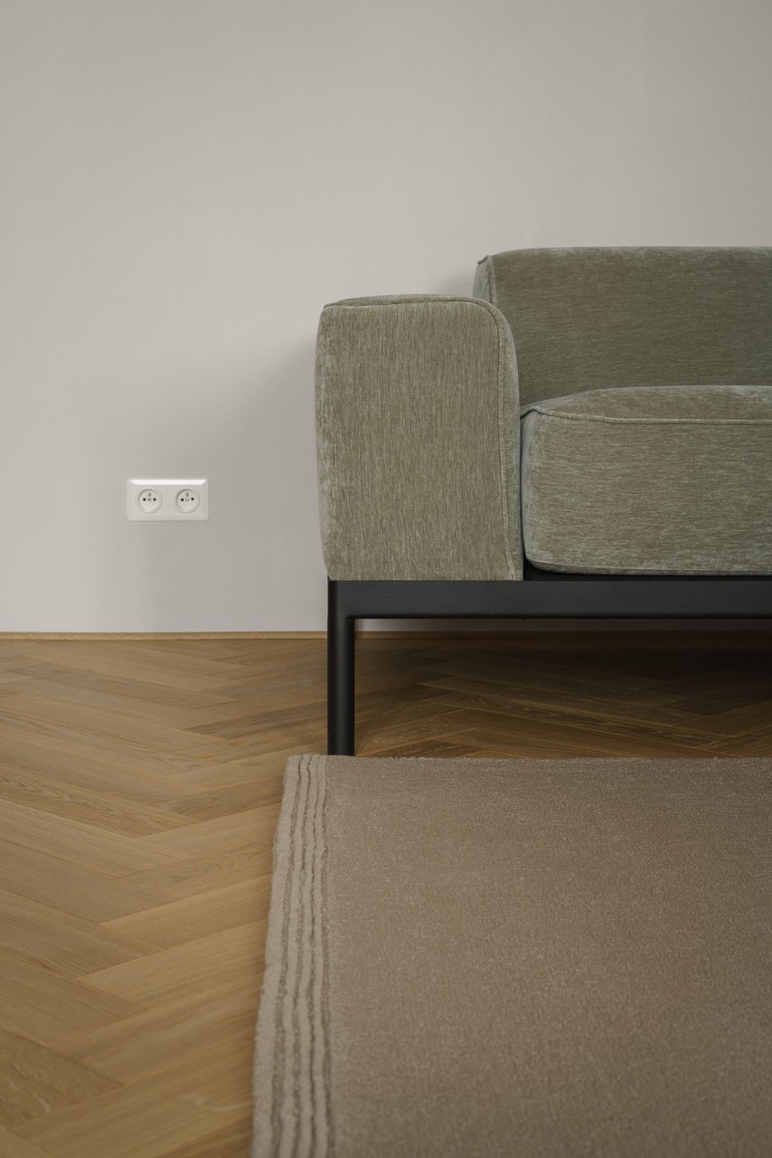 Szara sofa i drewniana podłoga w nowoczesnym wystroju wnętrz.