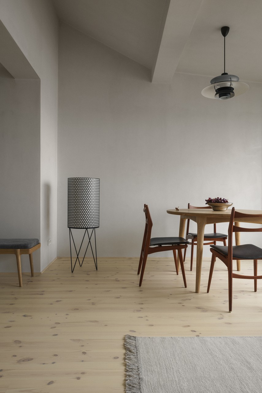 Minimalistyczne wnętrze z drewnianymi meblami i designerską lampą.