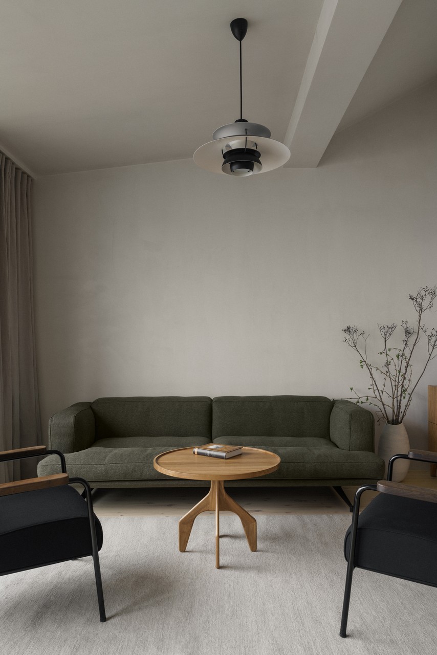 Elegancki salon z oliwkową sofą i designerskim oświetleniem.