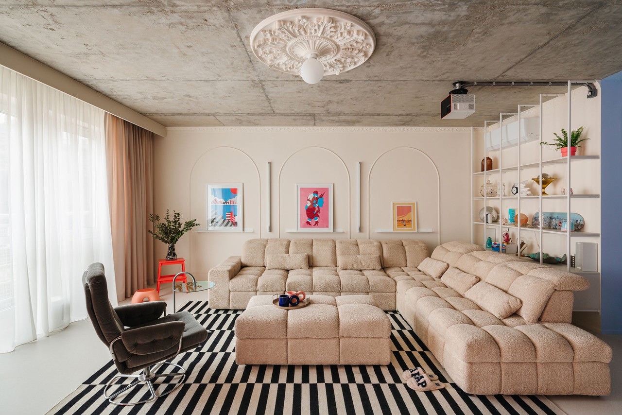 Nowoczesny salon z beżową sofą i geometrycznymi ozdobami ściany.