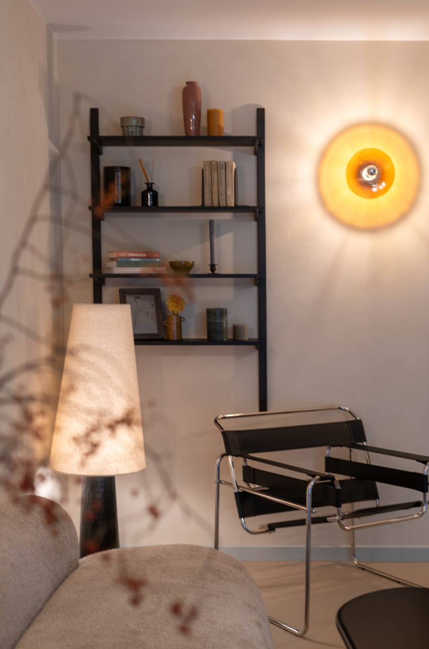 Elegancki salon z półkami, lampą i wygodnymi meblami.