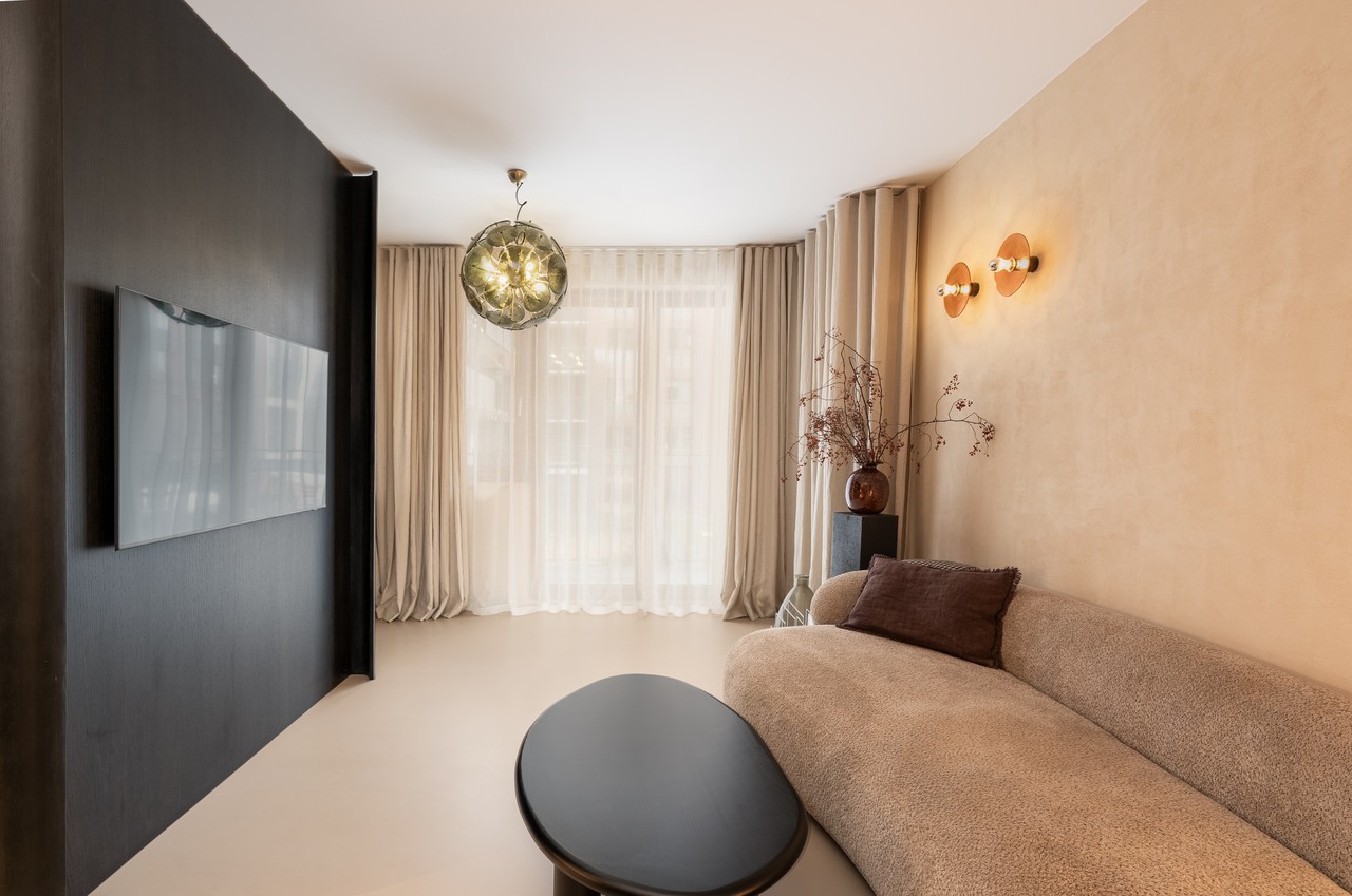 Nowoczesny salon z designerską lampą i eleganckimi zasłonami.