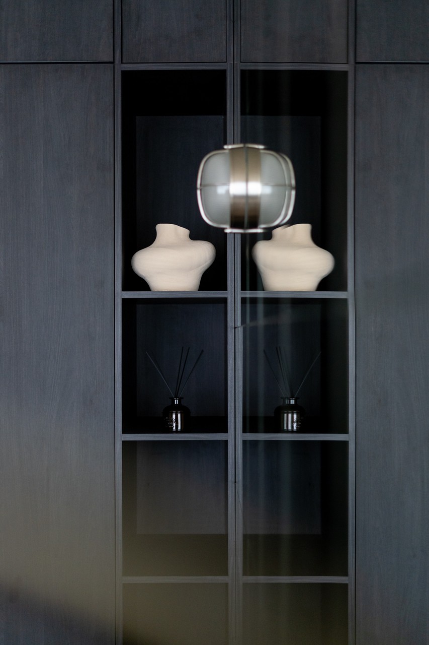 Elegancka półka z rzeźbami i nowoczesną lampą wiszącą.