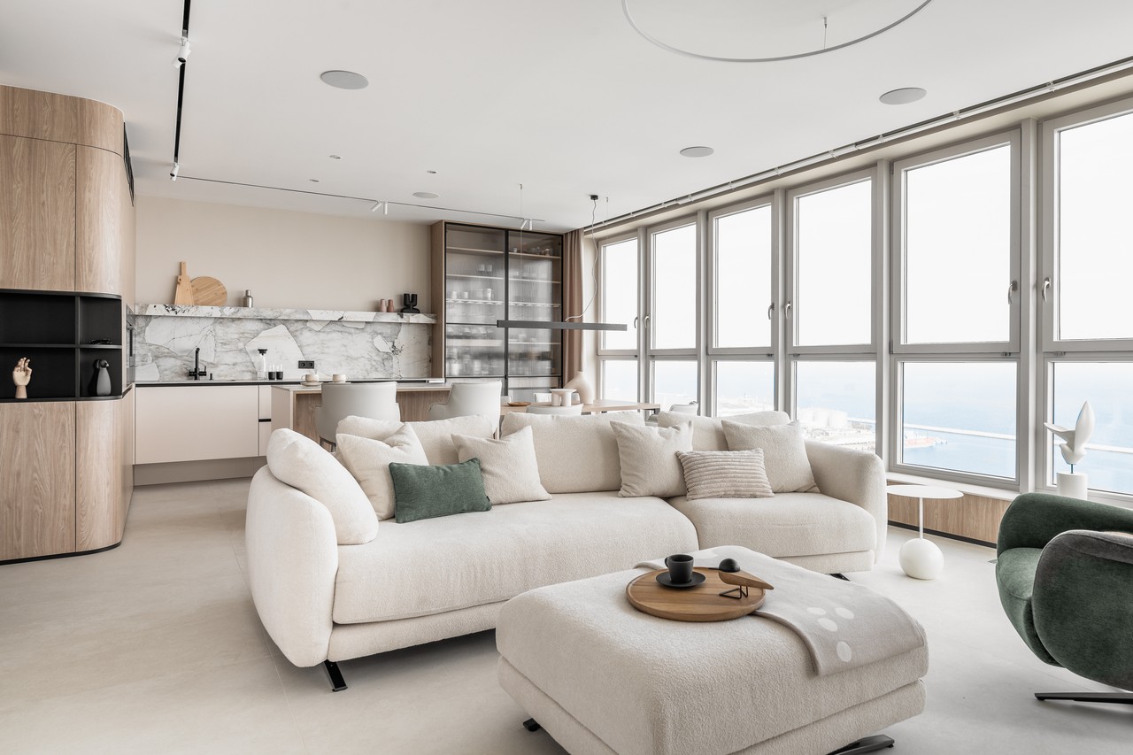 Nowoczesny salon z widokiem na morze, elegancka sofa w jasnych barwach.