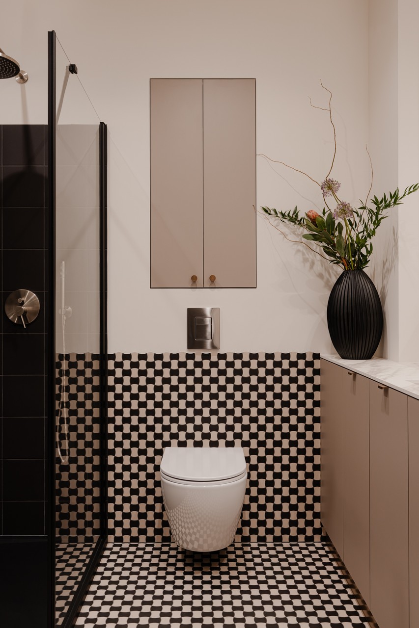 Nowoczesna łazienka z czarno-białą mozaiką i elegancką ceramiką.
