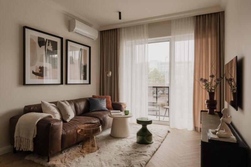Elegancki salon z brązową sofą i nowoczesnymi stolikami.