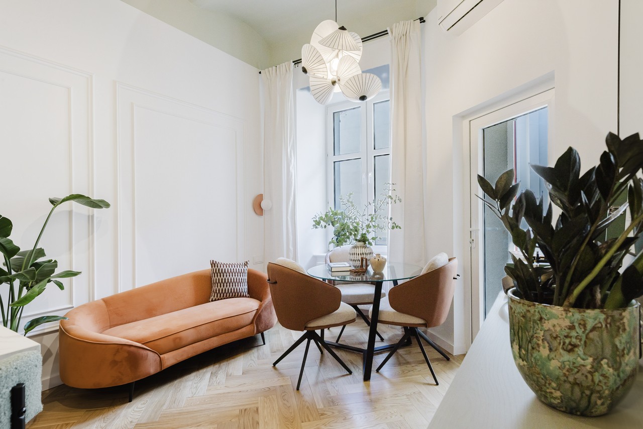 Przytulny salon z sofą w kolorze terakoty i designerskimi lampami.
