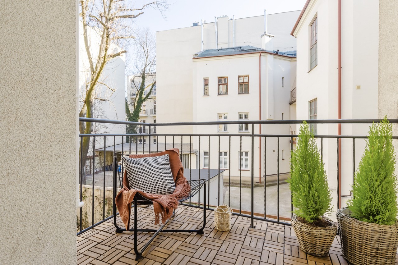 Przytulny balkon z krzesłem i roślinami w koszach.