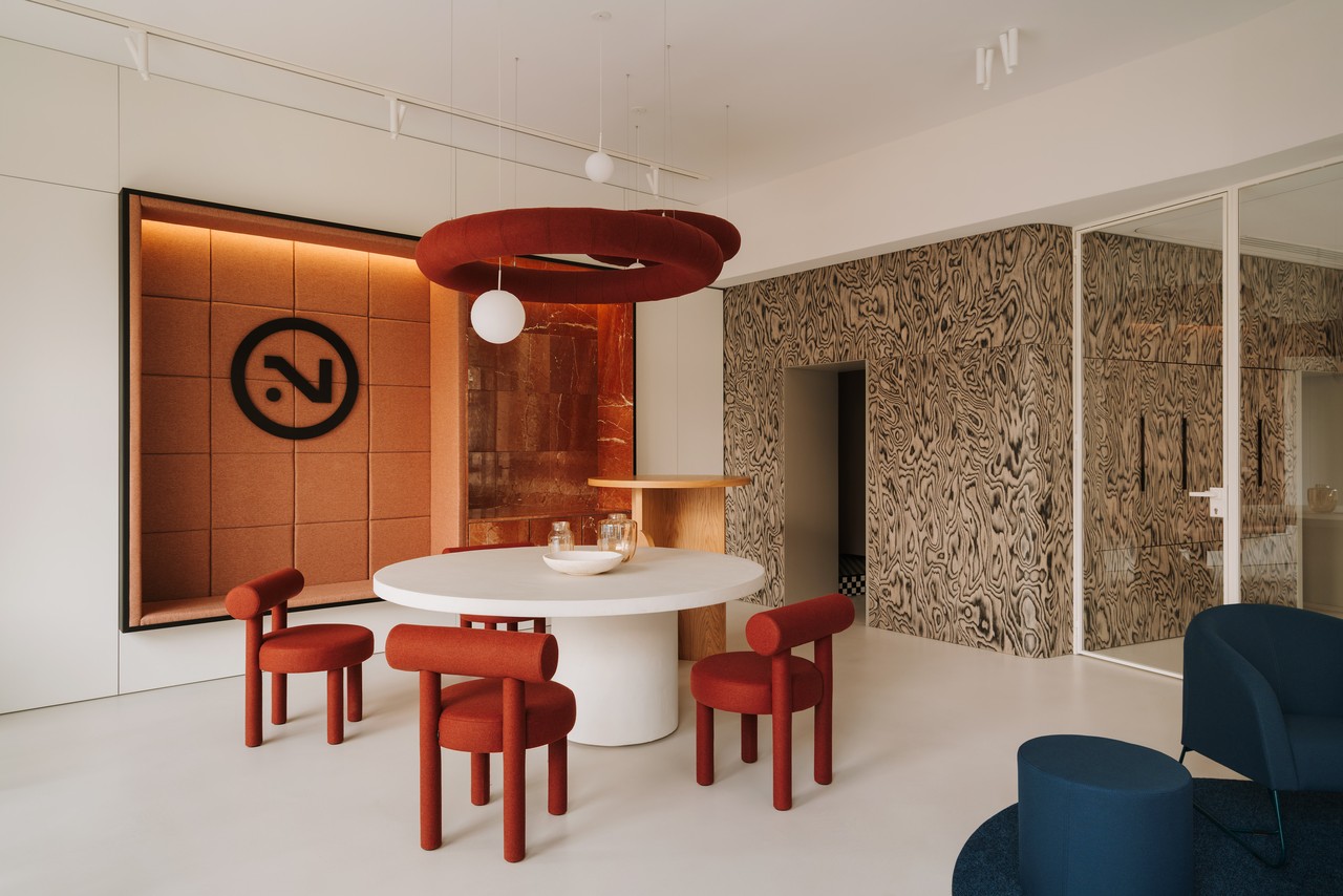 Stylowa jadalnia z czerwonymi krzesłami i designerskimi lampami.