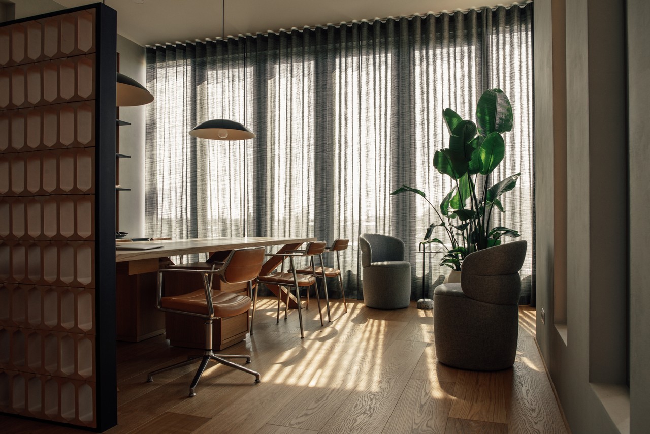 Elegancki salon z dużymi oknami, zielenią i drewnianym stołem.