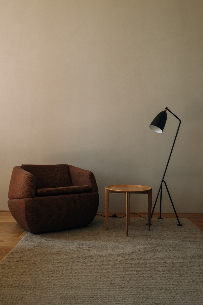 Nowoczesny fotel, lampa stojąca i stolik w minimalistycznym wnętrzu.