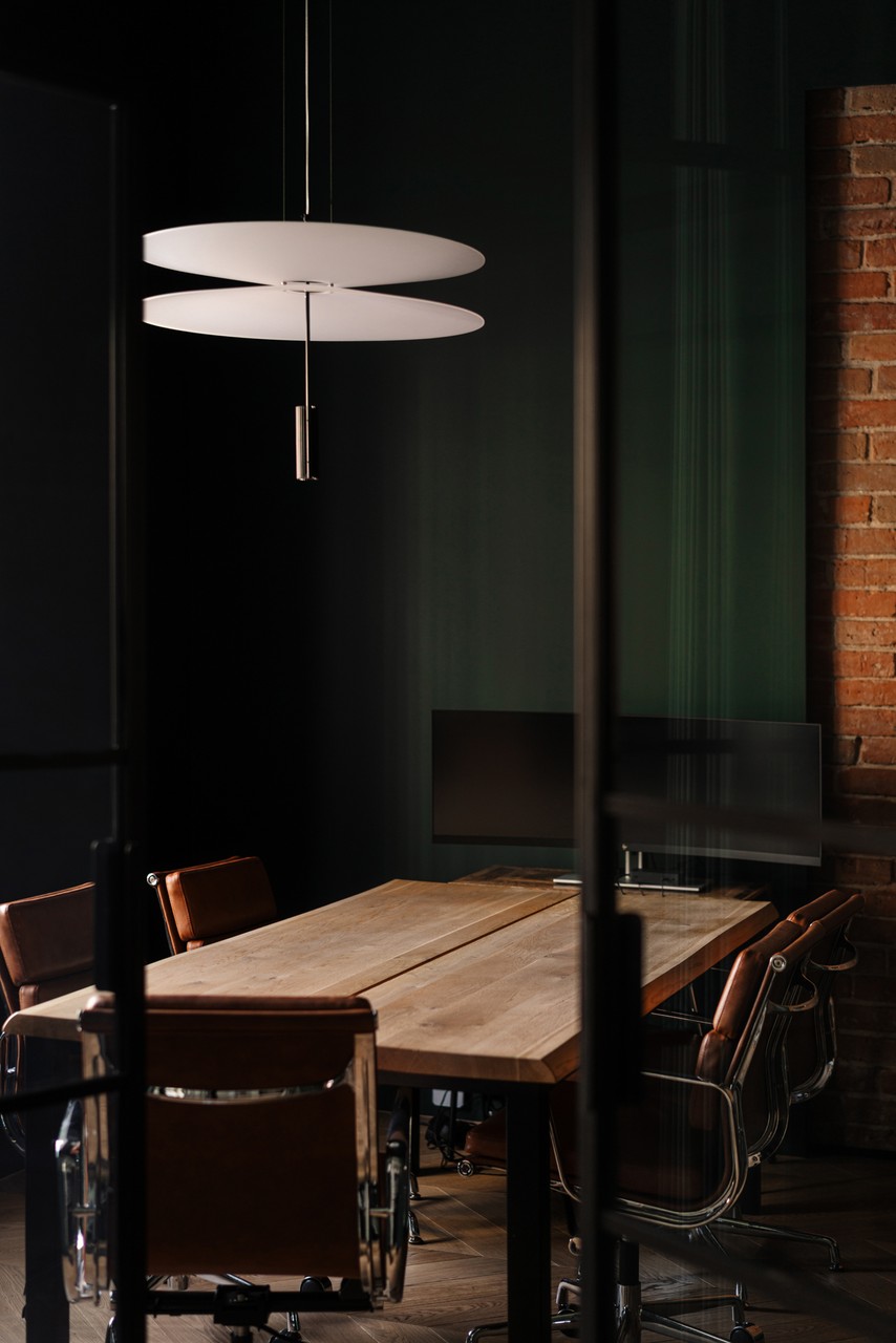 Nowoczesne biuro, drewniany stół i designerska lampa wisząca.