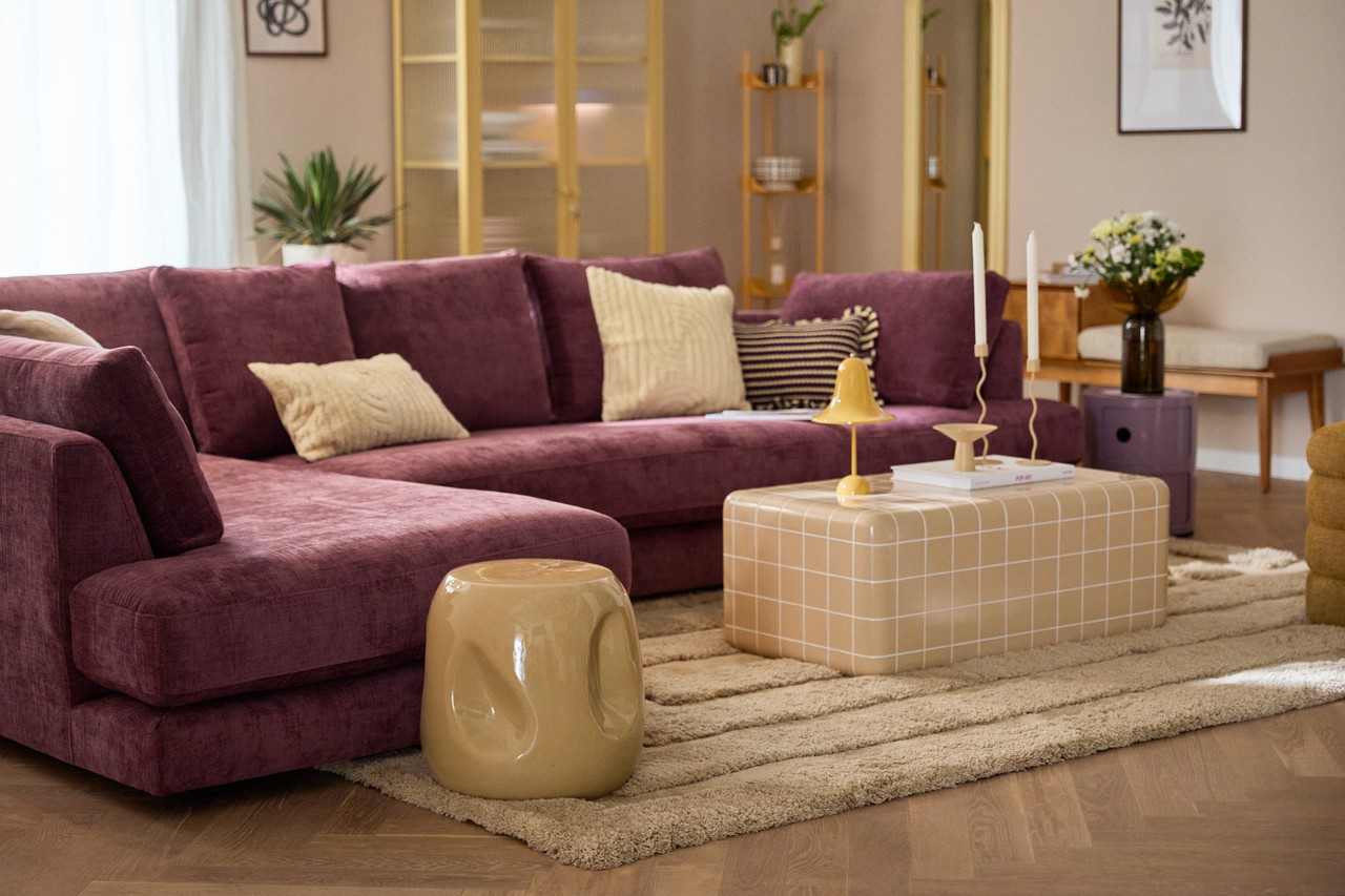 Elegancki salon z fioletową sofą i designerskimi dodatkami.