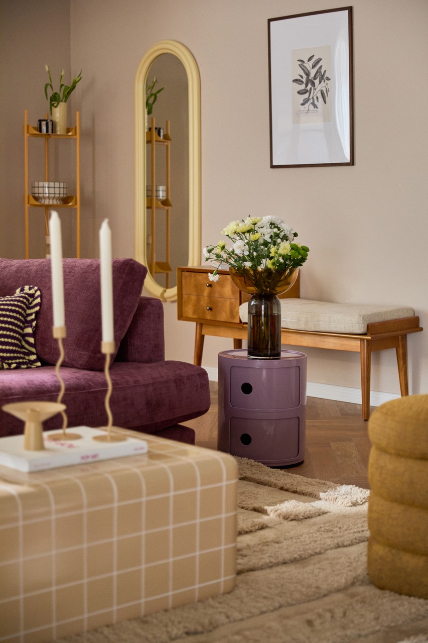 Elegancki salon z fioletową sofą i kwiatowymi dekoracjami.