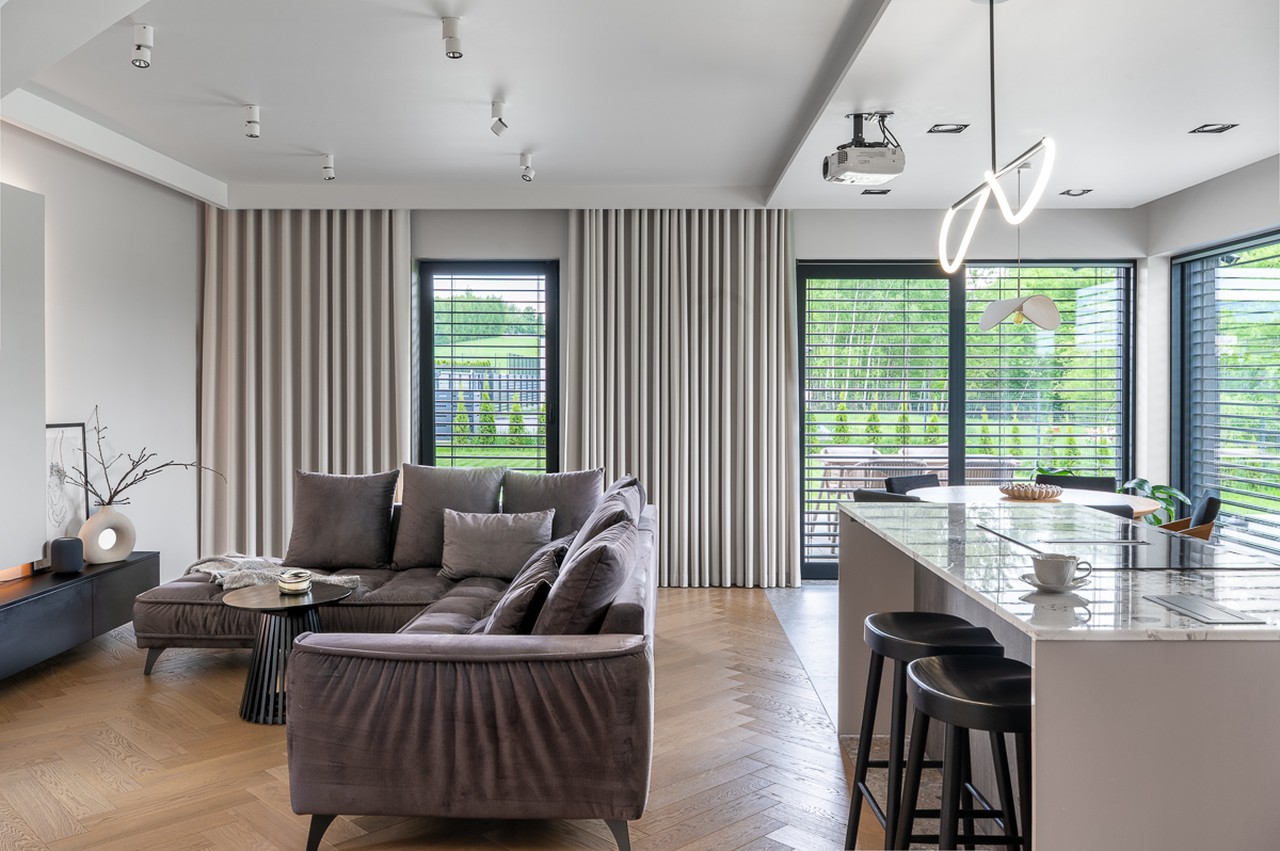 Nowoczesny salon z elegancką sofą i wyspą kuchenną.