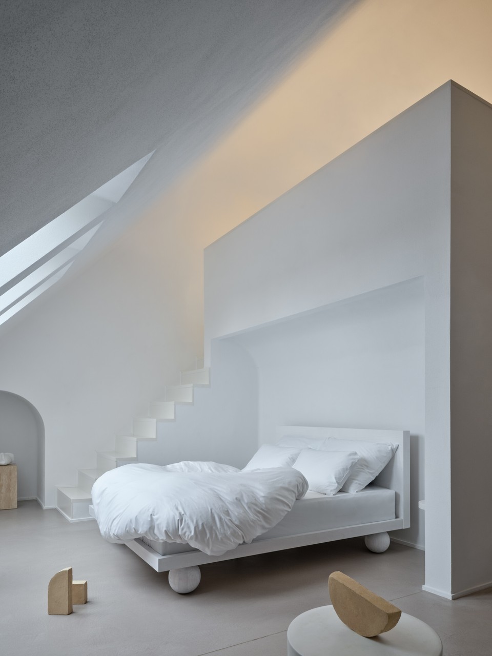 Minimalistyczna sypialnia z designerskim łóżkiem i naturalnym oświetleniem.