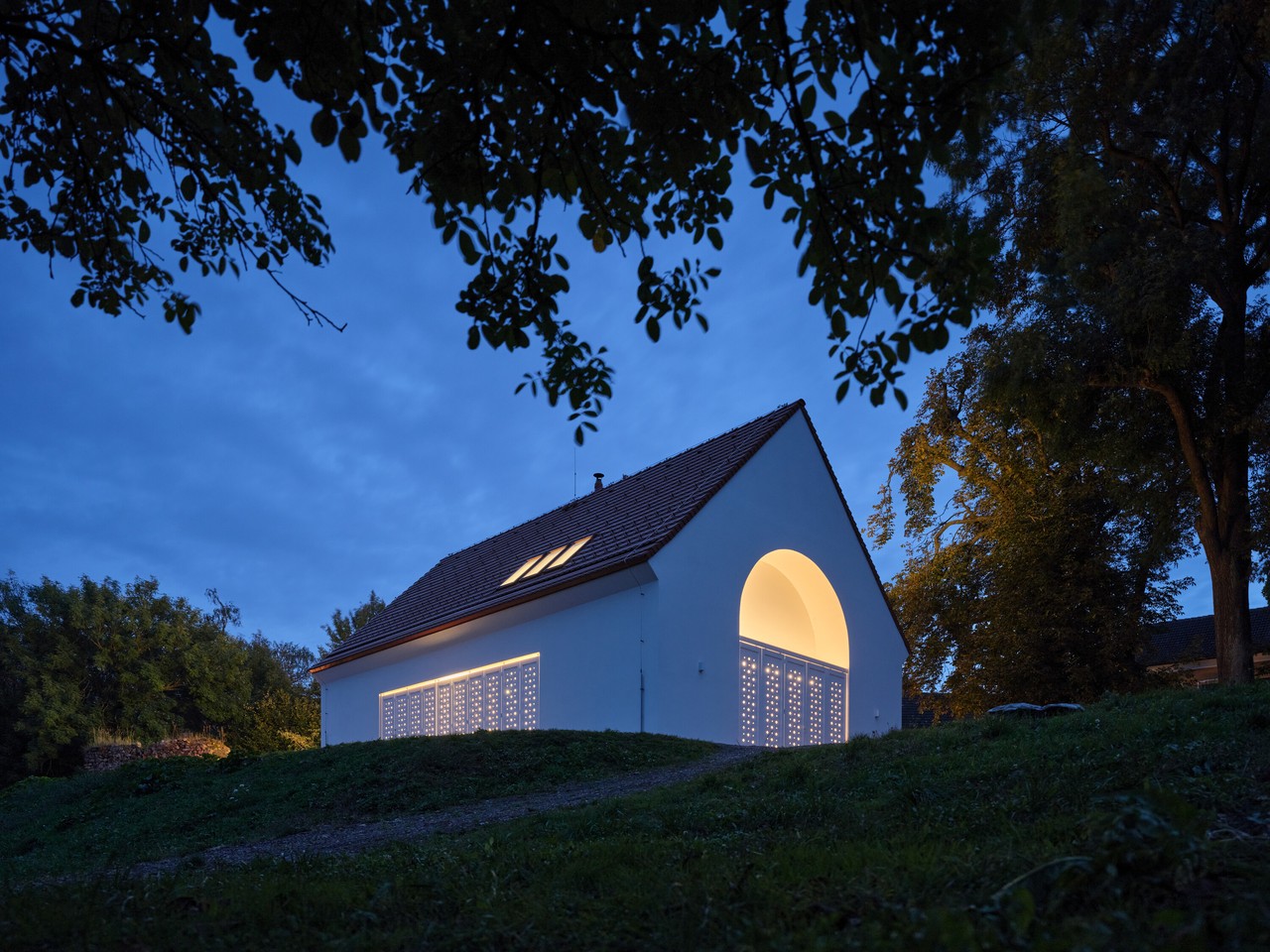 Przytulny domek z oświetleniem, wieczorny pejzaż architektoniczny.