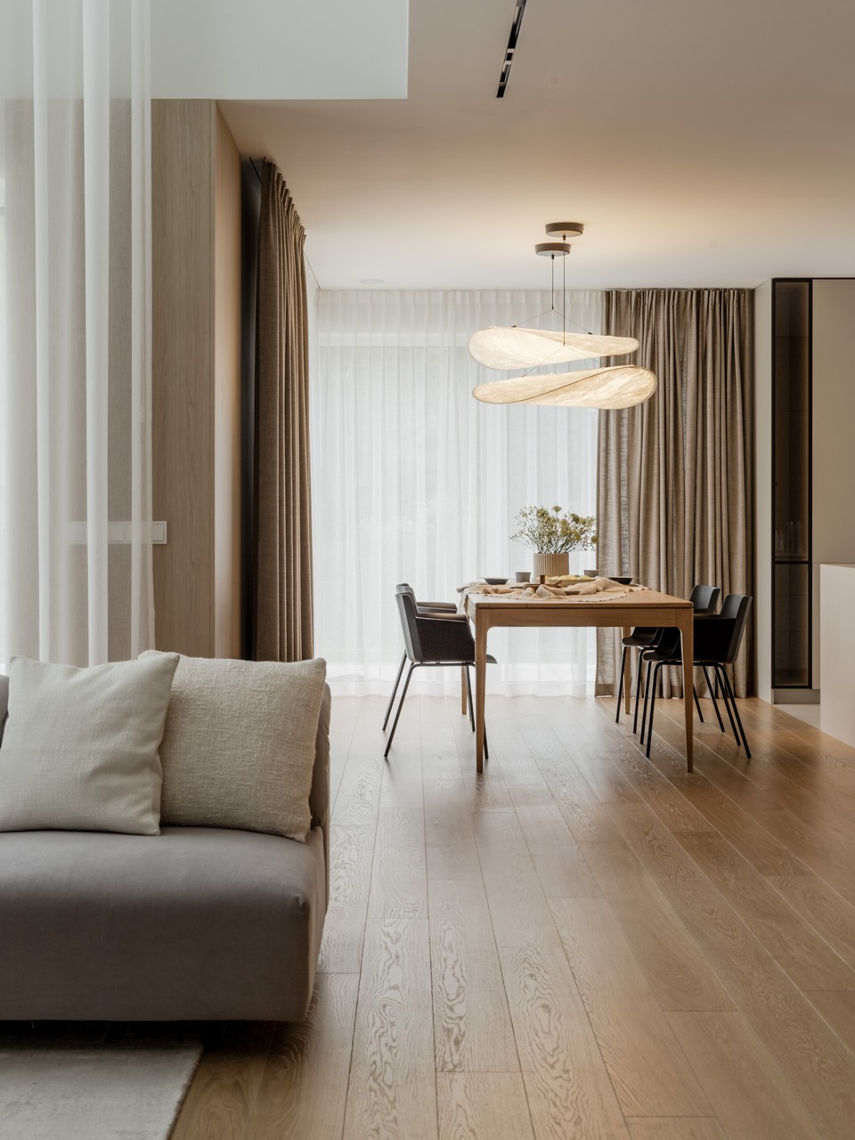 Jasne wnętrze z drewnianą podłogą i designerskim oświetleniem.