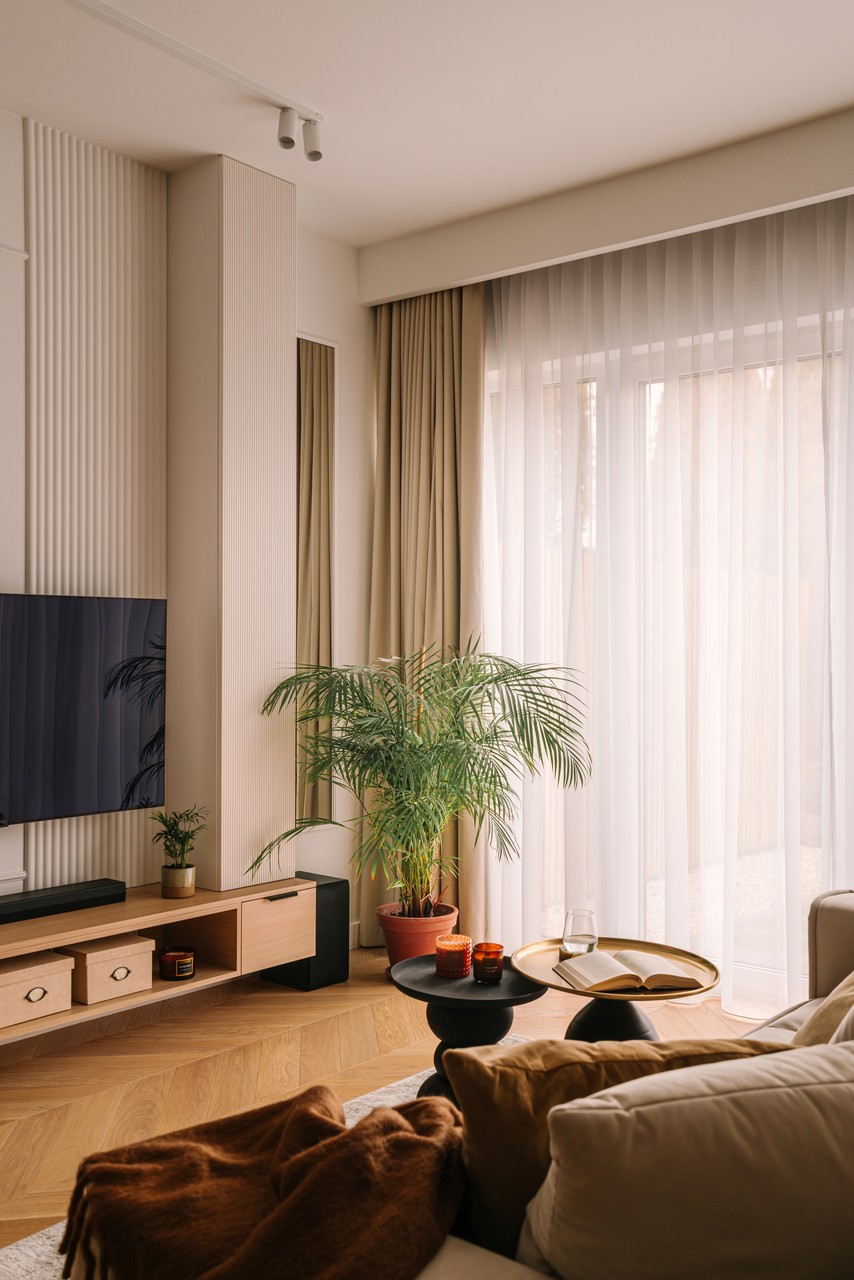 Elegancki salon z roślinami i drewnianym stolikiem.