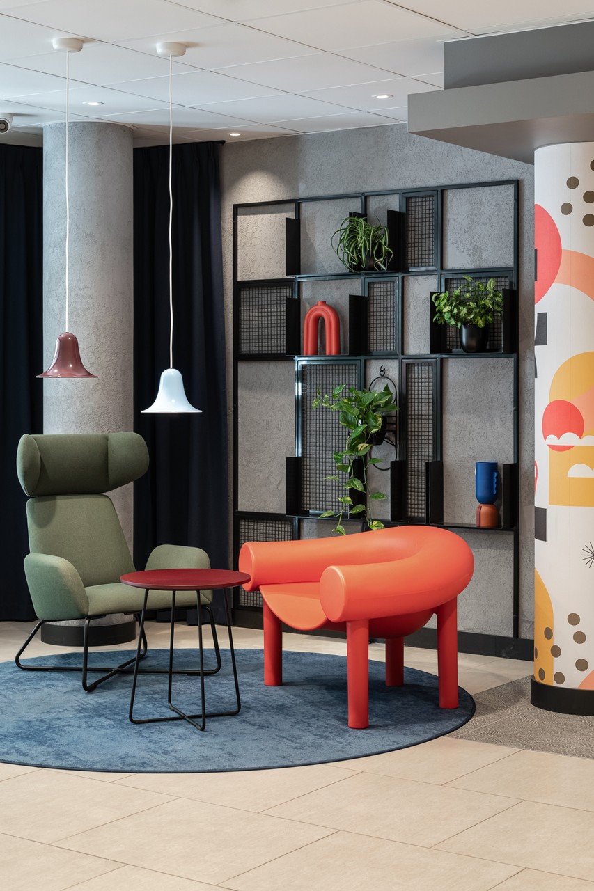 Nowoczesny salon z kolorowym fotelem i designerskimi lampami.