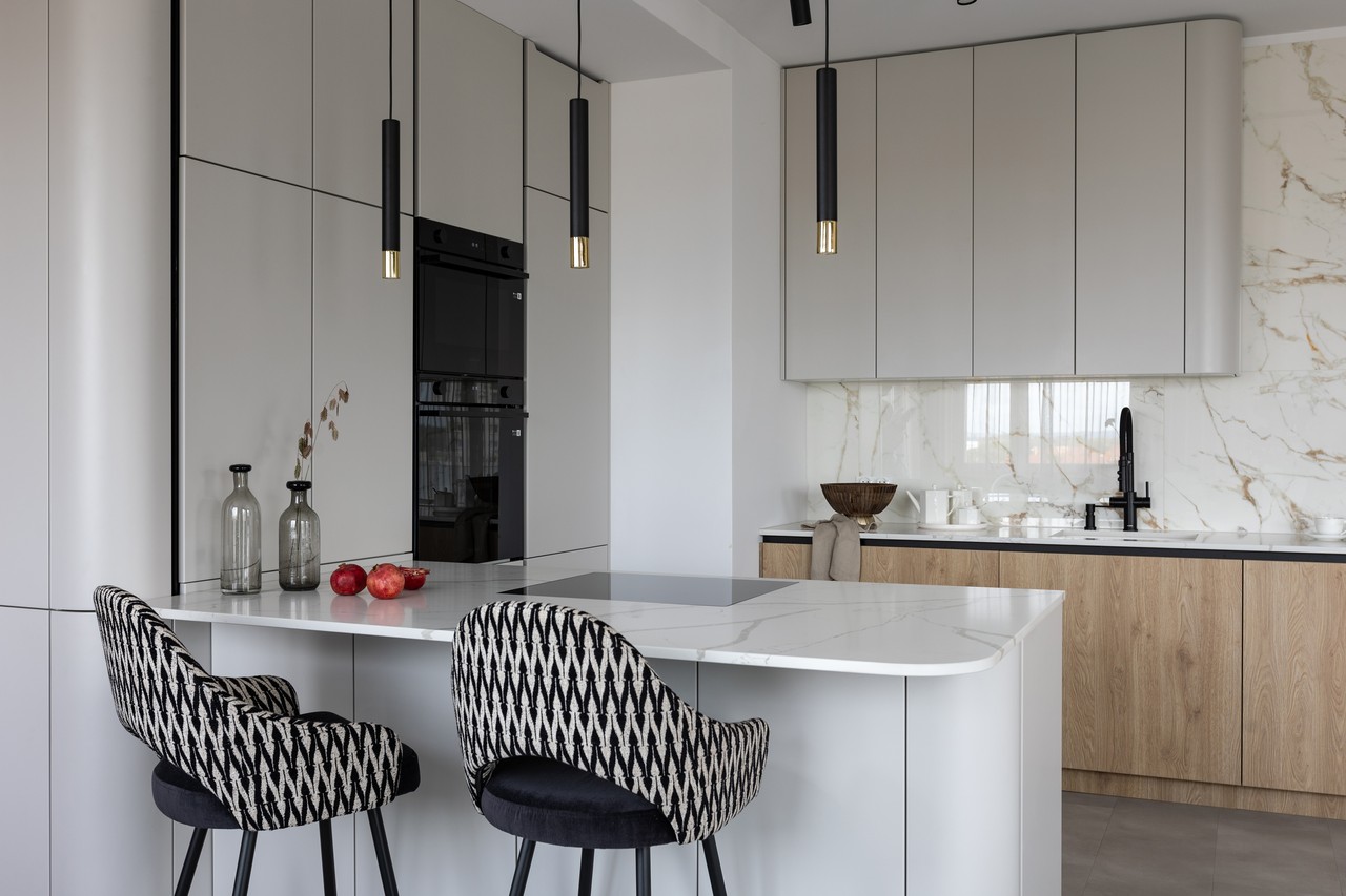 Modern kitchen with island, elegant cabinets, patterned chairs.