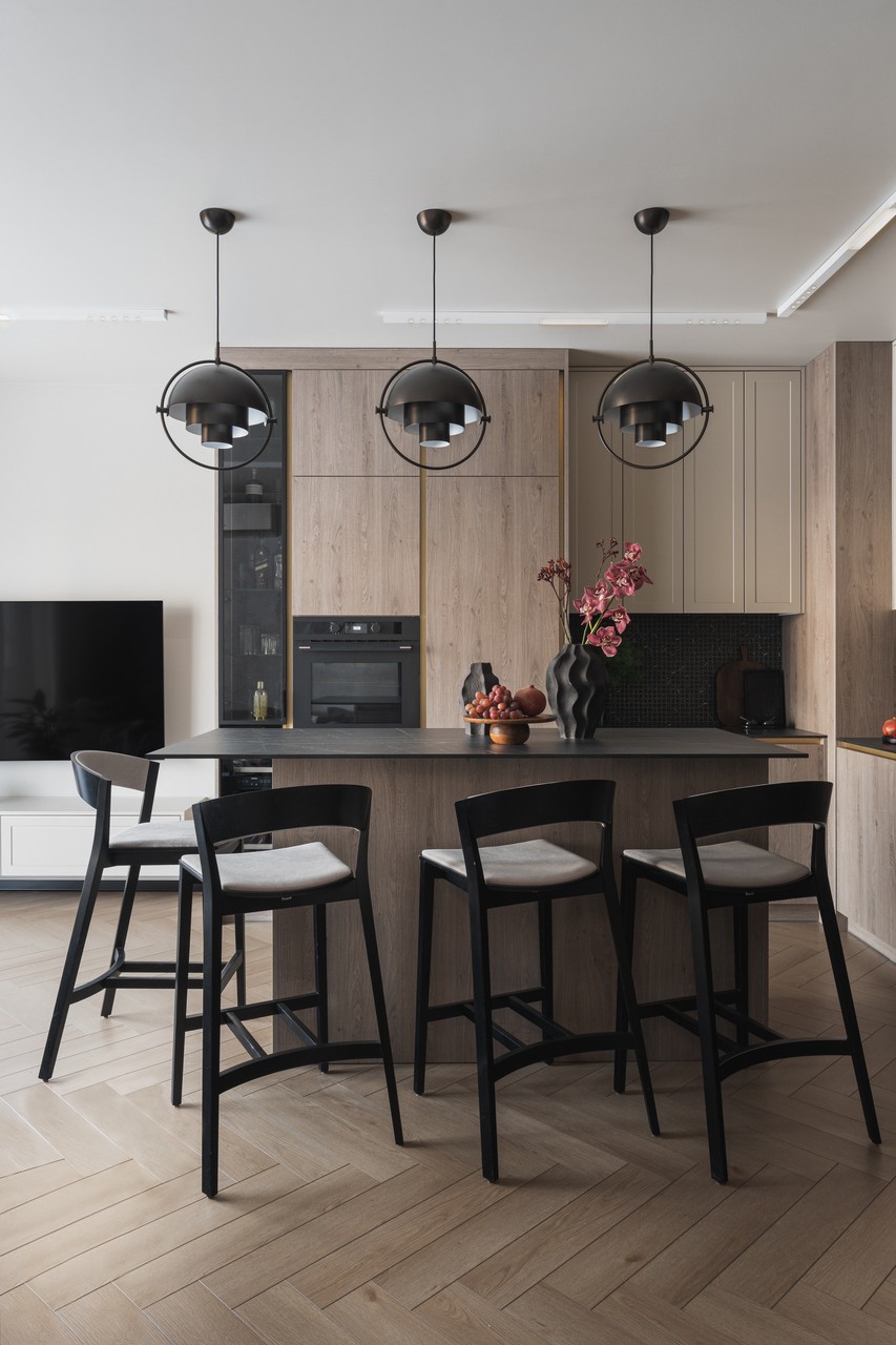 Modern kitchen with wooden finish and elegant lamps.