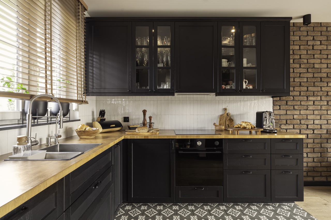 Black cabinets with a brick wall, a modern kitchen with character.