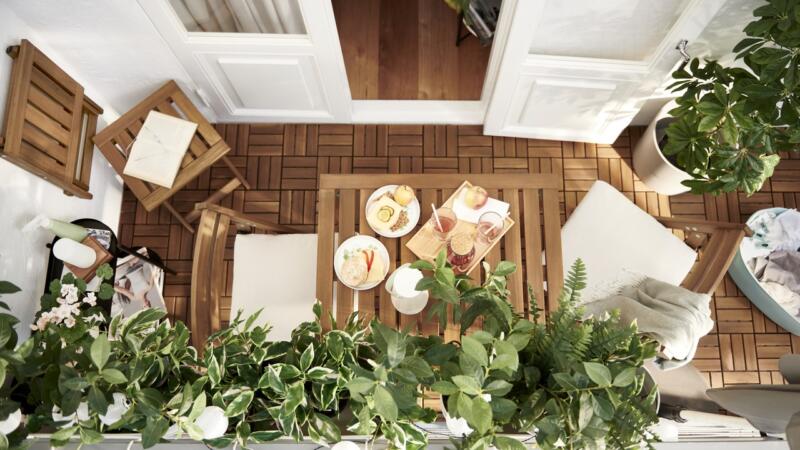 Przytulny balkon z drewnianymi meblami i zielonymi roślinami.