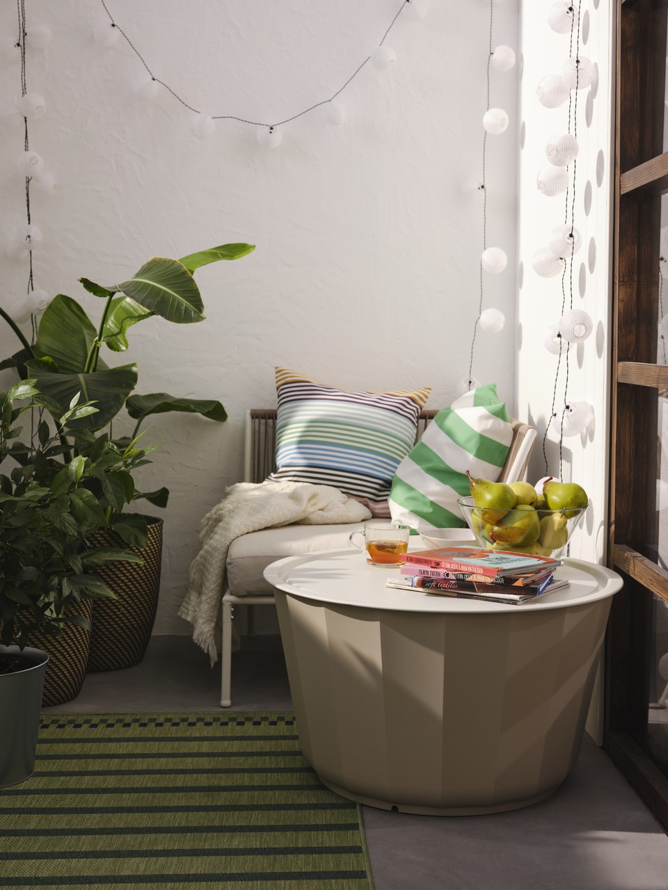 Przytulny balkon z roślinami i designerskimi poduszkami.
