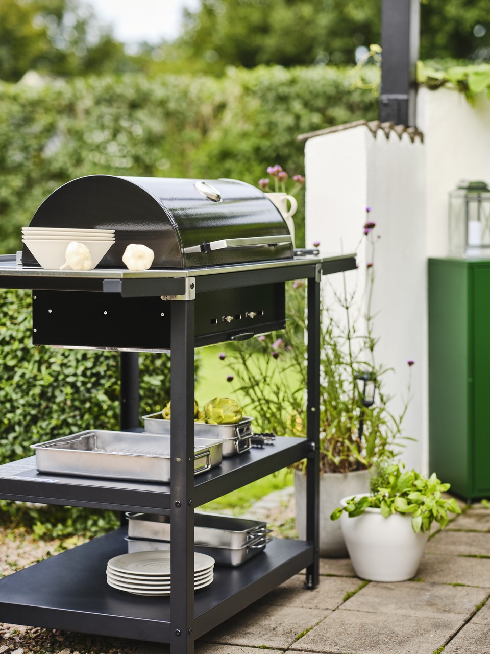 Grill ogrodowy na tarasie w otoczeniu zieleni.