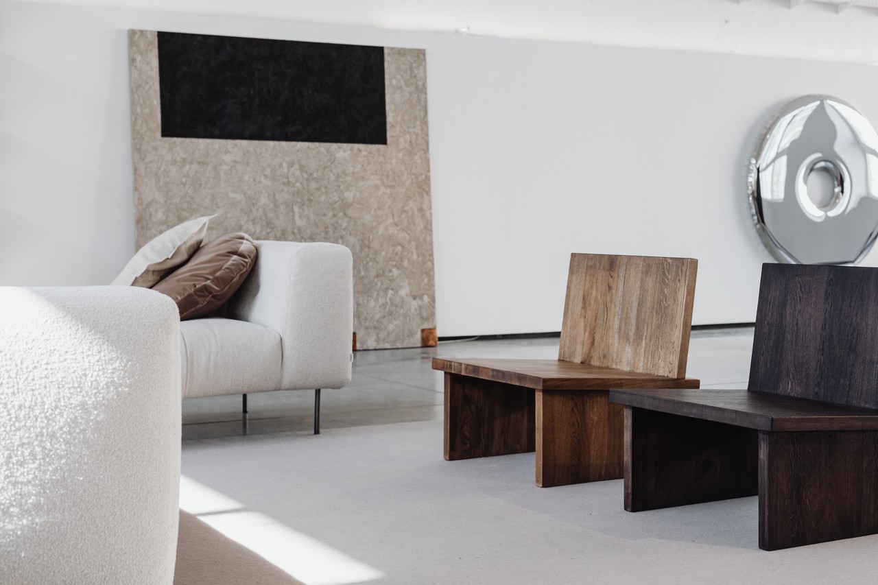 Minimalistyczny salon z nowoczesnymi meblami i drewnianymi krzesłami.