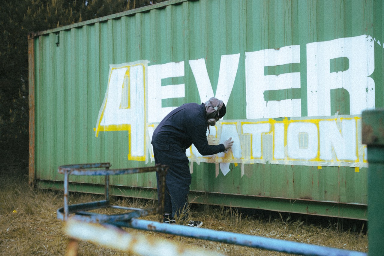 Artystyczne graffiti na zielonym kontenerze w trakcie tworzenia.