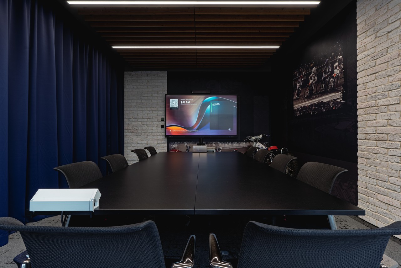 Nowoczesna sala konferencyjna z ekranem i designerskimi krzesłami.