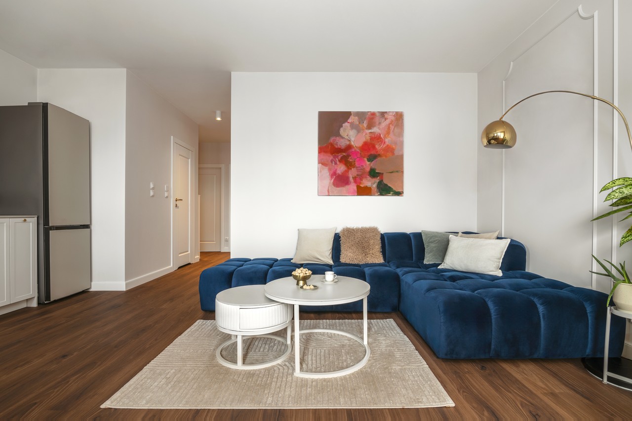 Elegancki salon z niebieską sofą i złotą lampą stojącą.